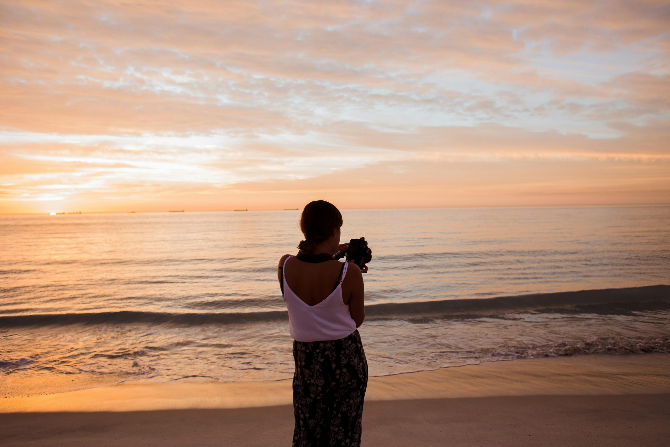 woman capturing the sunset on the beach