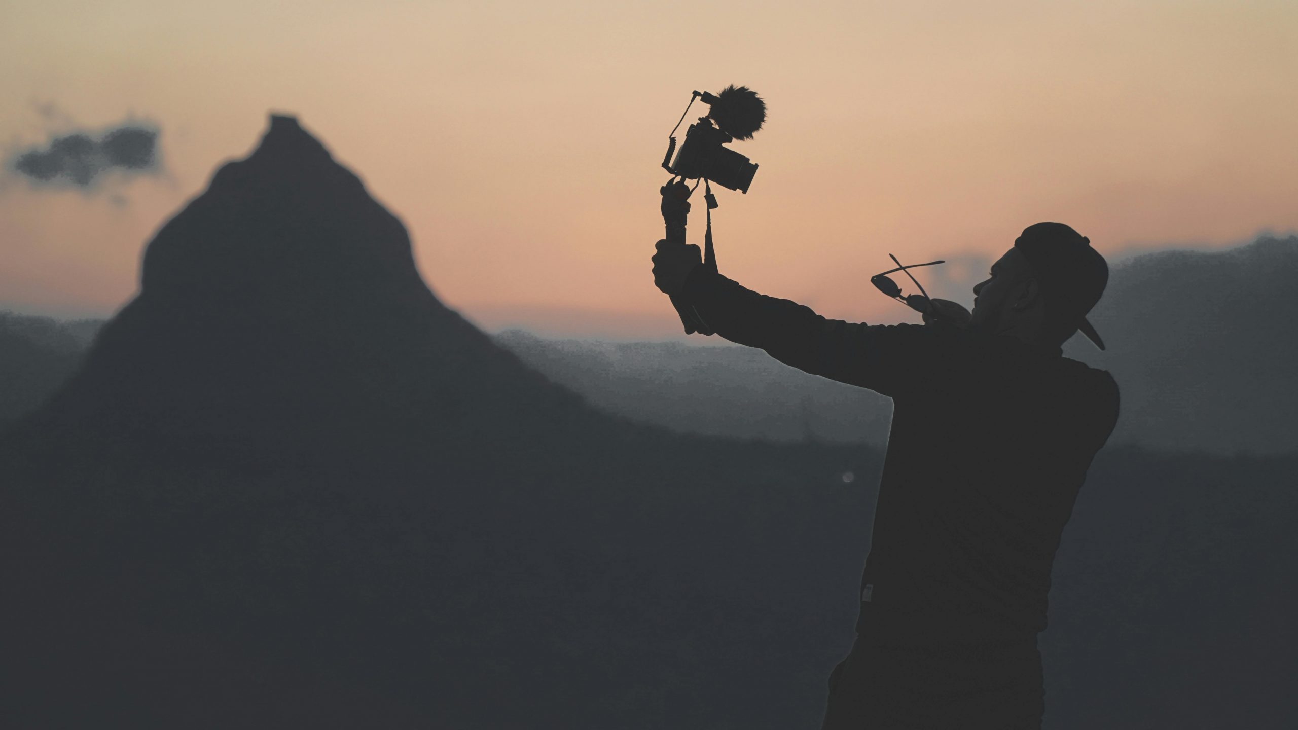 silhouette of a man holding a camera with a mountain in the background