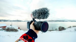 hand gripping a camera, surrounded by snow-covered scenery